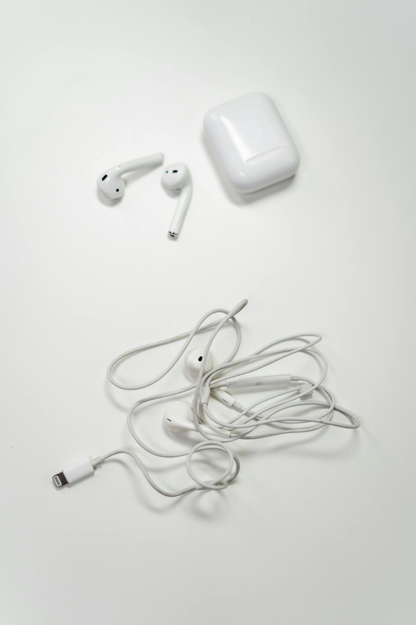 Overhead view of wireless and wired earbuds on a white background, showcasing modern audio technology.